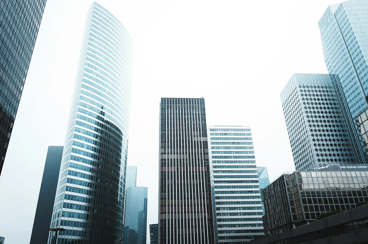 A series of large, glass skyscrapers against a clear white sky.