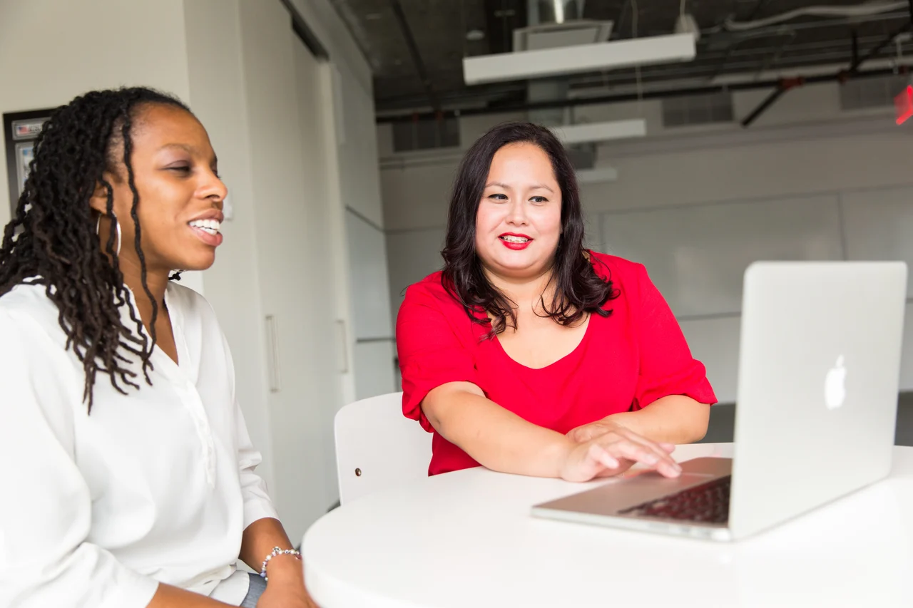 Two colleagues sit around a laptop.