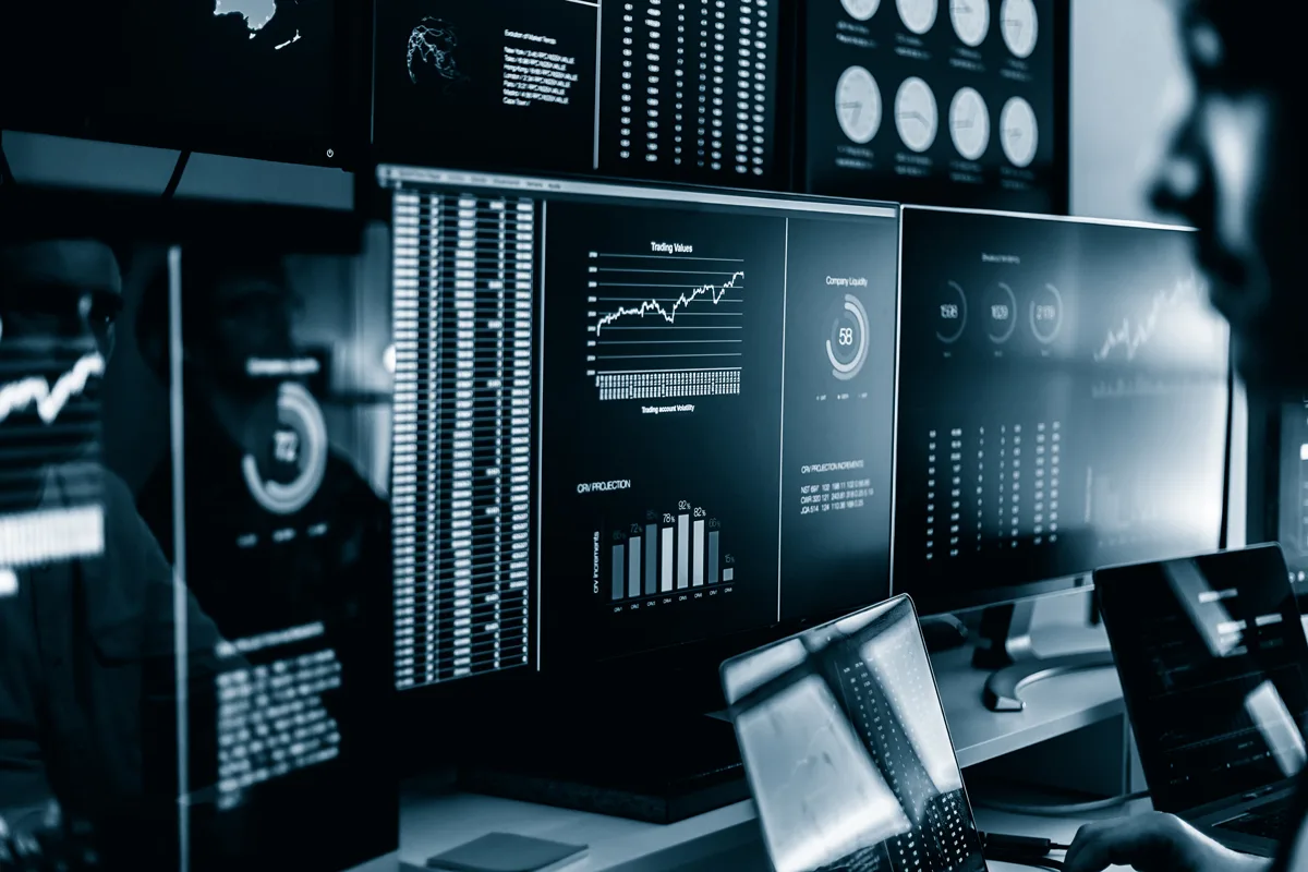 A person looking at data on multiple monitors.